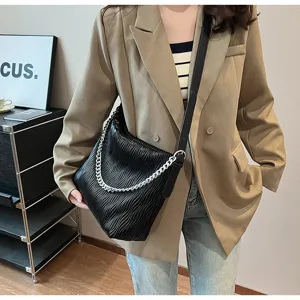Detailed shot of a black pleated fashion shoulder bag with silver chain for women, autumn style.