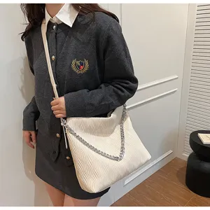 Detailed view of white pleated shoulder bag with metallic chain strap and soft texture.