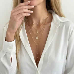 Multi-layer gold necklace with starfish and shell pendants and pearls for summer vacation.