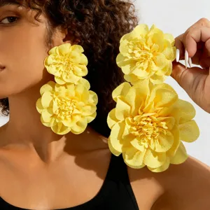 Detailed macro view showing the textured yellow fabric layers of large floral drop earrings