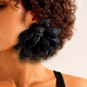 Close-up of a large black fabric flower earring on a model, showcasing its intricate petals.