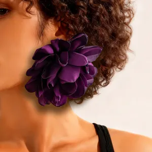 Close-up of a large, vibrant purple fabric flower earring on a model, showing fine textures.