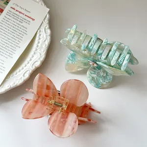 Close-up detail of stylish acetate butterfly hair claws in green and pink, perfect for spring.