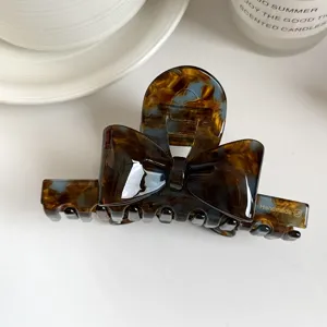 Tortoiseshell bow hair claw clip detail shot, elegant cellulose acetate hair accessory closeup.