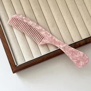 Detailed close-up of pink acetate hair comb, convenient handle design with smooth teeth.