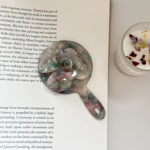 Primer plano detallado del espejo de maquillaje floral portátil de acetato con rosa.