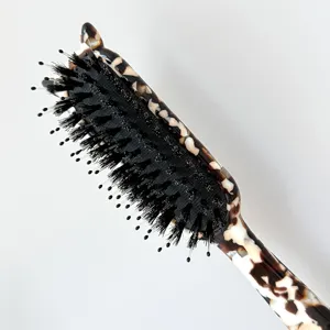 Close-up detail of tortoise shell hair brush showing fine bristles and smooth handle.