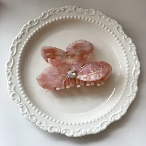 Pink acetate butterfly flower hair claw clip detail view, featuring sparkling rhinestone center.