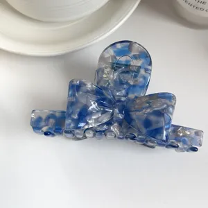 Blue acetate hair claw clip with 3D bow design, elegant marble pattern hairpin detail view.