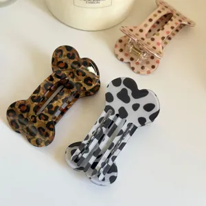Gros plan de pinces a cheveux tendance en forme d'os avec des imprimes leopard et pois chics.