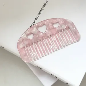 Nahaufnahme eines rosa Acetat-Haarkamms mit süssen Herz-Ausschnitten, elegant und handlich.