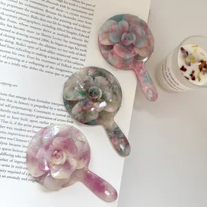 Primer plano detallado del espejo de maquillaje portatil estetico de resina con rosas.