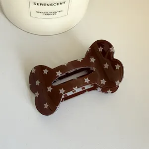 Gros plan détaillé de la pince à cheveux os marron avec motif d'étoiles, design élégant.