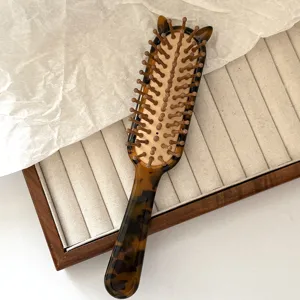 Tortoiseshell hair brush detail showing cute cat ears and bristle pins, elegant styling tool.