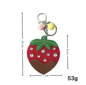 Dettaglio portachiavi fragola con strass, ciondolo per borsa con anello in metallo e perline colorate.