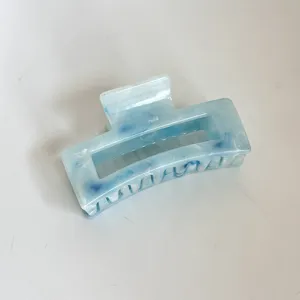 Vista detallada de pinza para el cabello de plástico marmoleado azul, brillante y elegante clip.