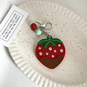 Primo piano dettagliato del portachiavi a fragola in strass con salsa di cioccolato.