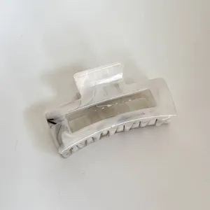 Primer plano de una elegante pinza para el cabello con patrón de mármol, acrílico brillante.