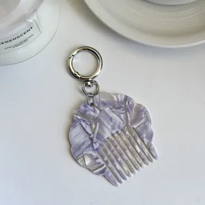 Detail view of the portable acetate shell comb keychain with a chic pearlescent marble finish.
