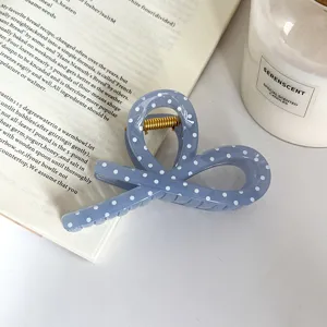 Vista dettagliata di una molletta per capelli blu a pois bianchi, elegante e chic.