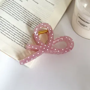 Vista dettagliata di una molletta per capelli rosa a pois con fiocco, elegante.