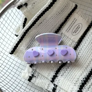 Vue détaillée de la pince à cheveux à carreaux violets avec des breloques cœur et strass.