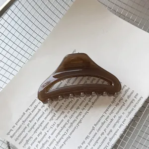 Λεπτομερής λήψη μιας καφέ διαφανούς κοίλης και καμπύλης τσιμπίδας μαλλιών σε χαρτί.