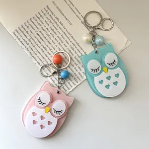 Primo piano dettagliato di simpatici portachiavi specchio gufo in rosa e azzurro.