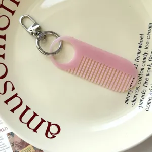 Gedetailleerd overzicht van een schattige roze mini kam sleutelhanger, draagbare haarhanger.