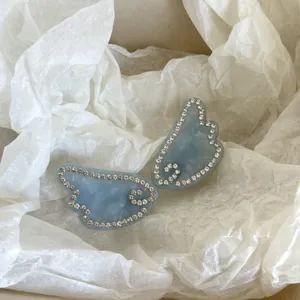 Blue rhinestone angel wing hair clip detail view, sparkling crystal side pin accessory.