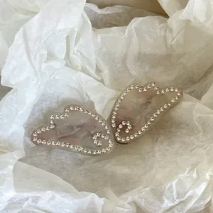 Detailed closeup of rhinestone angel wing acetate hair clip, exquisite sparkling crystal hair accessory.