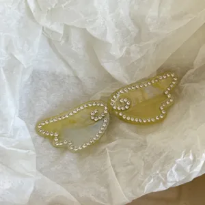 Close-up detail of the rhinestone angel wings hair clip, sparkling crystal details on acetate.