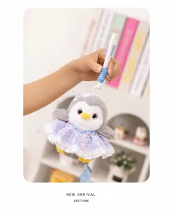 Cute plush penguin doll wearing a floral dress and apron, hanging toy detail.