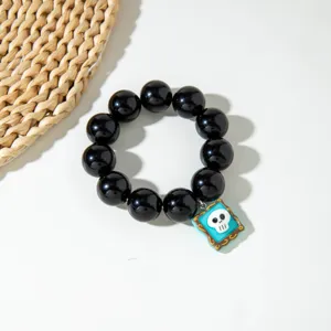 Gros plan sur bracelet d'Halloween en perles noires brillantes avec un pendentif crâne.