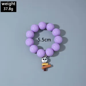Gros plan sur un bracelet en perles acryliques violettes avec pendentif tête de mort Halloween
