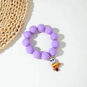 Gros plan d'un bracelet d'Halloween en perles acryliques mauves avec pendentif tête de mort