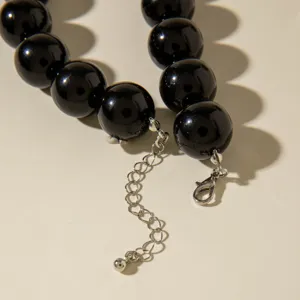 Vue détaillée d'un collier en perles acryliques noires avec fermoir mousqueton argenté