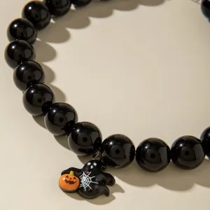 Gros plan d'un bracelet d'Halloween en perles noires avec breloques fantôme et citrouille