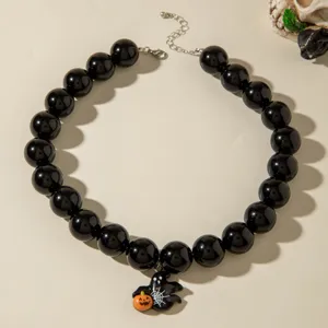 Gros plan d'un collier de perles noires d'Halloween avec pendentif citrouille.