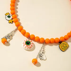 Gros plan sur un collier de perles orange d'Halloween avec des breloques fantômes