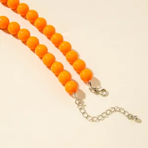 Gros plan d'un collier en perles acryliques orange vif avec fermoir mousqueton argenté