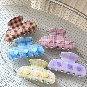 Gros plan de pinces à cheveux à carreaux avec cœurs mignons et strass scintillants pour femmes.