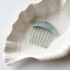 Detail shot of blue acetate crown hair comb with sparkling rhinestones and metal teeth.