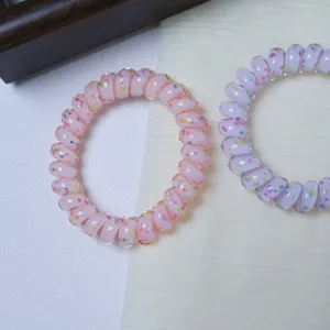 Detailed view of colorful polka dot telephone cord hair ties in pink and purple tones.