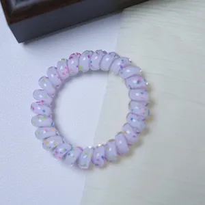 Detailed view of the cute purple telephone wire hair tie with colorful polka dot accents.
