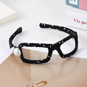 Detailansicht des schwarz-weißen Pünktchen-Brillengestell-Haarbands mit Perlen als Accessoire.