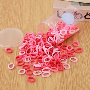 Kids colorful hair rubber bands in clear storage jar, sweet candy style, detail view.