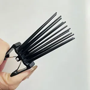 Detail shot of black plastic hair root volumizing clip with multi-pronged teeth for styling bangs.