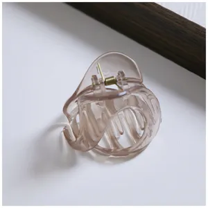 Detailed close-up of a transparent brownish-grey hair claw clip, showing its unique shape.