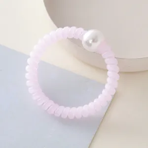 Primo piano dettagliato di un elastico per capelli a spirale rosa con perla bianca.